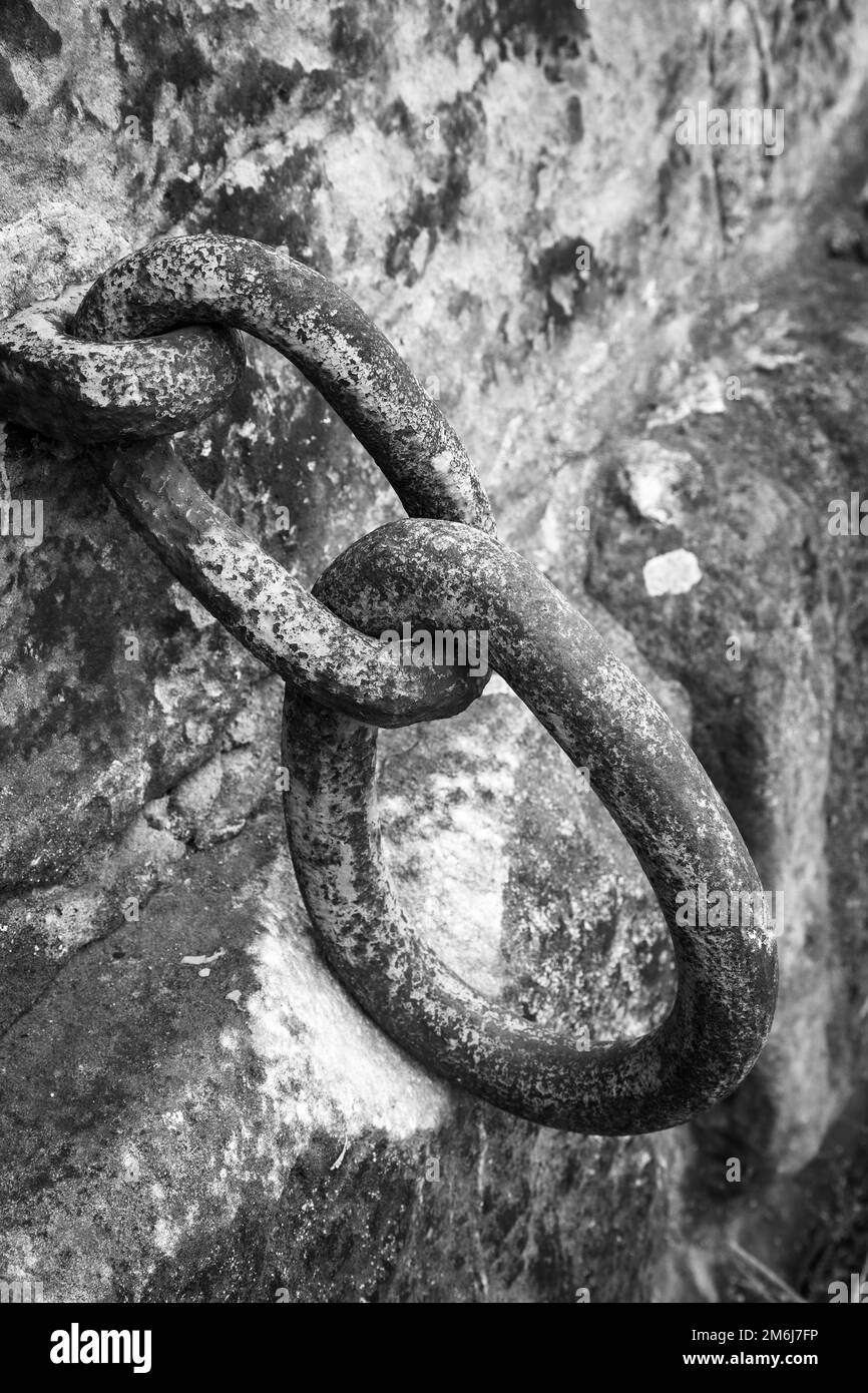 Immagini monocromatiche di vecchie maglie di catene di ferro, fissate ad un muro di pietra sulla passerella del fiume che si avvicina al centro di Dresda, Sassonia, Germania Foto Stock