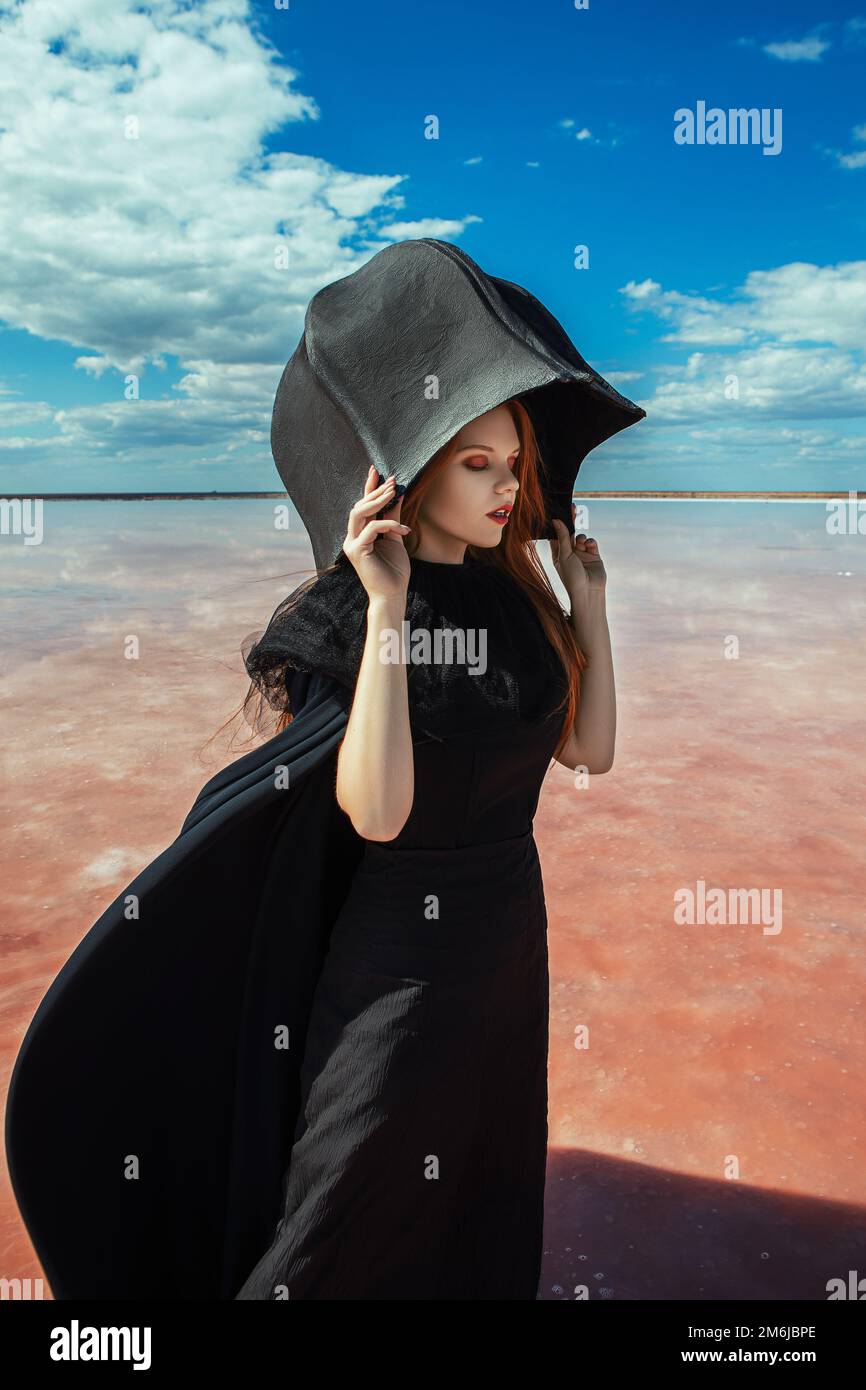 donna in un vestito nero su un lago rosa Foto Stock