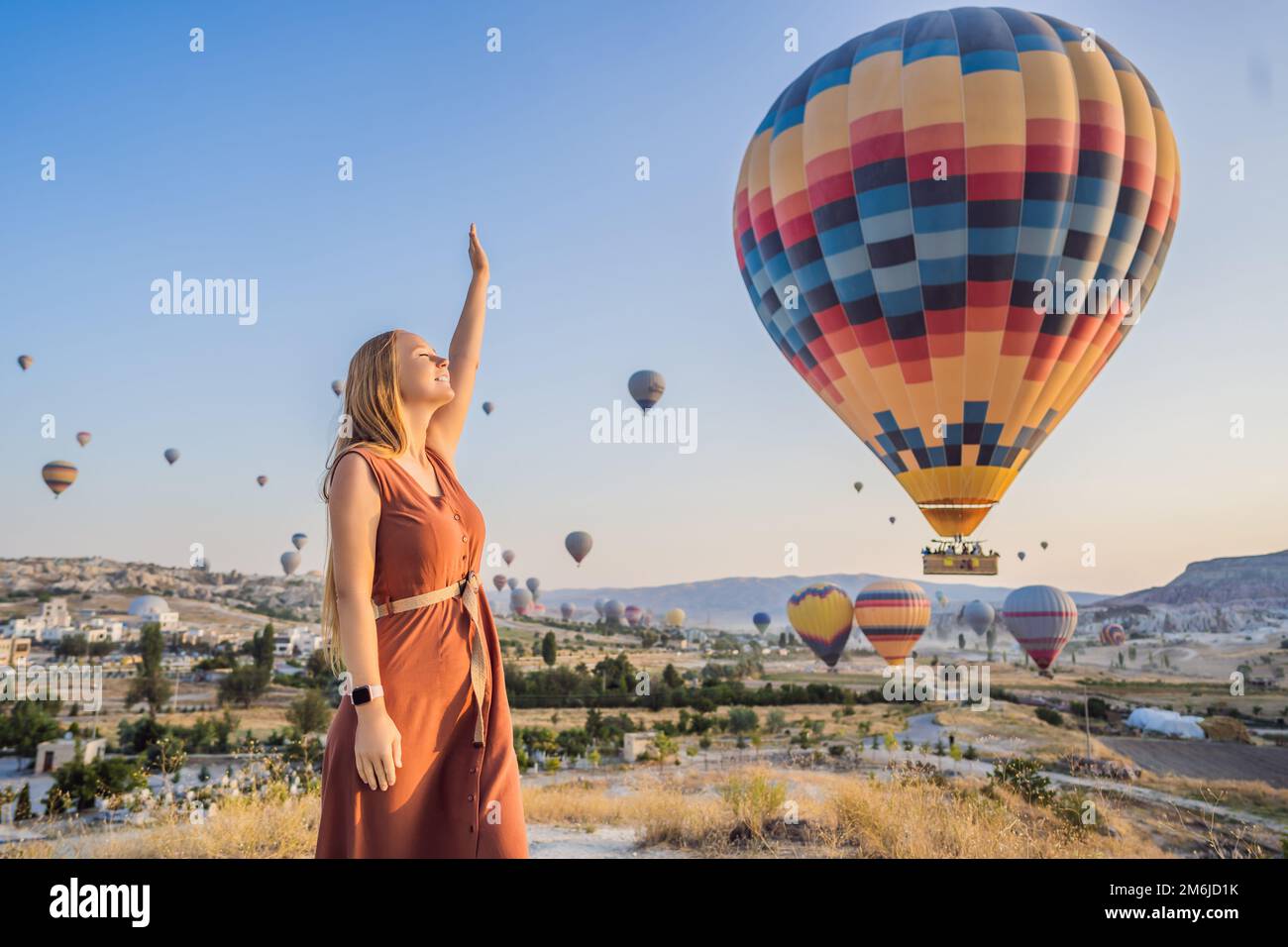 Donna turistica che guarda mongolfiere in Cappadocia, Turchia. Buon viaggio in Turchia concetto. Donna in cima a una montagna che gode di una vista meravigliosa Foto Stock