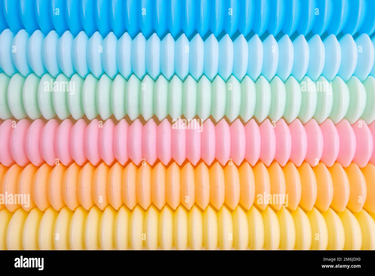 Giocattoli alla moda per bambini color pastello pop-tube su sfondo beige. Set di forme e colori corrugato tubo e anti-stress, relax Foto Stock