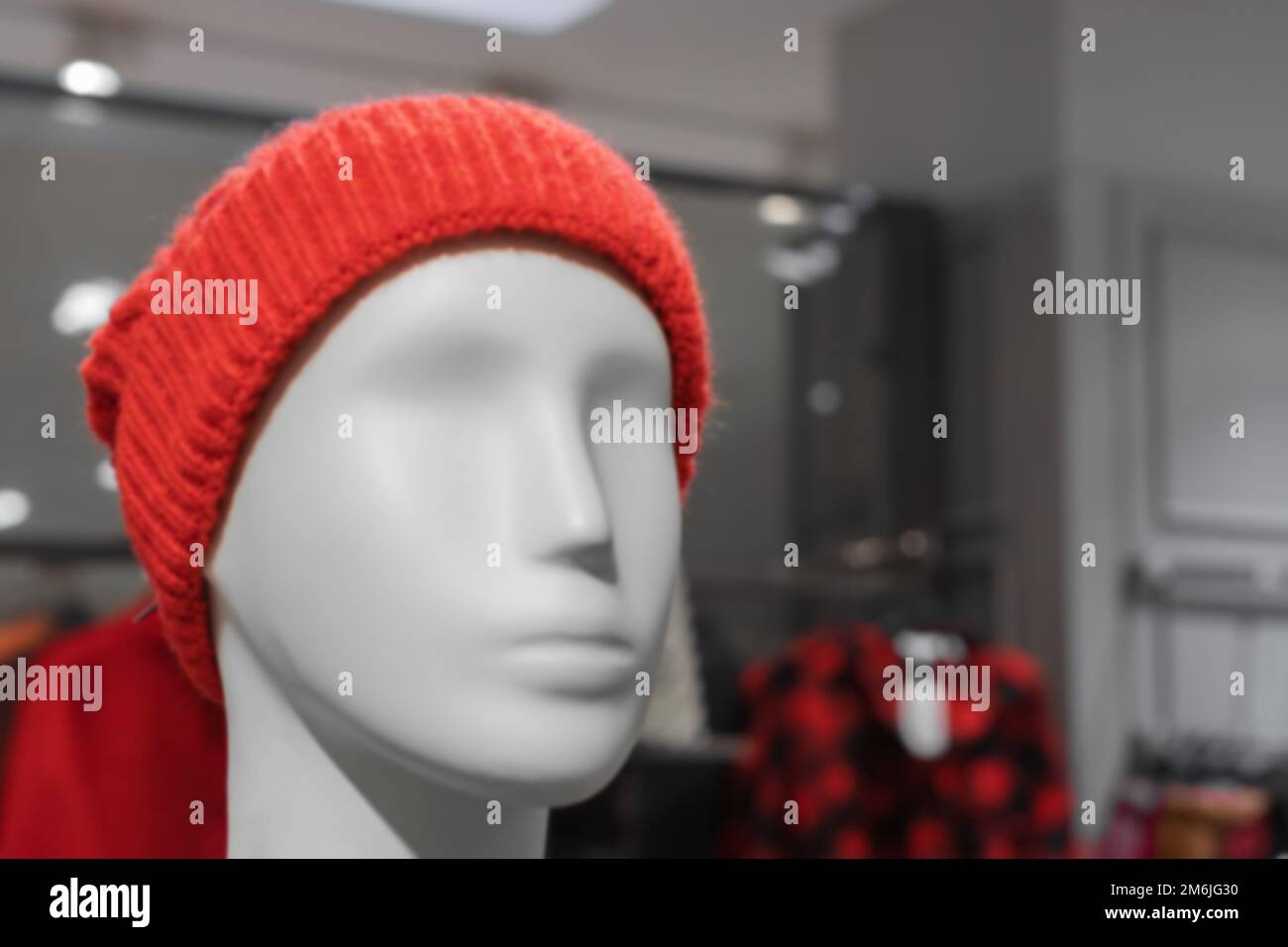 La testa di un manichino bianco maschio in un cappello a maglia rossa. Stile giovanile. Negozio di abbigliamento di moda. Foto sfocata. Foto Stock