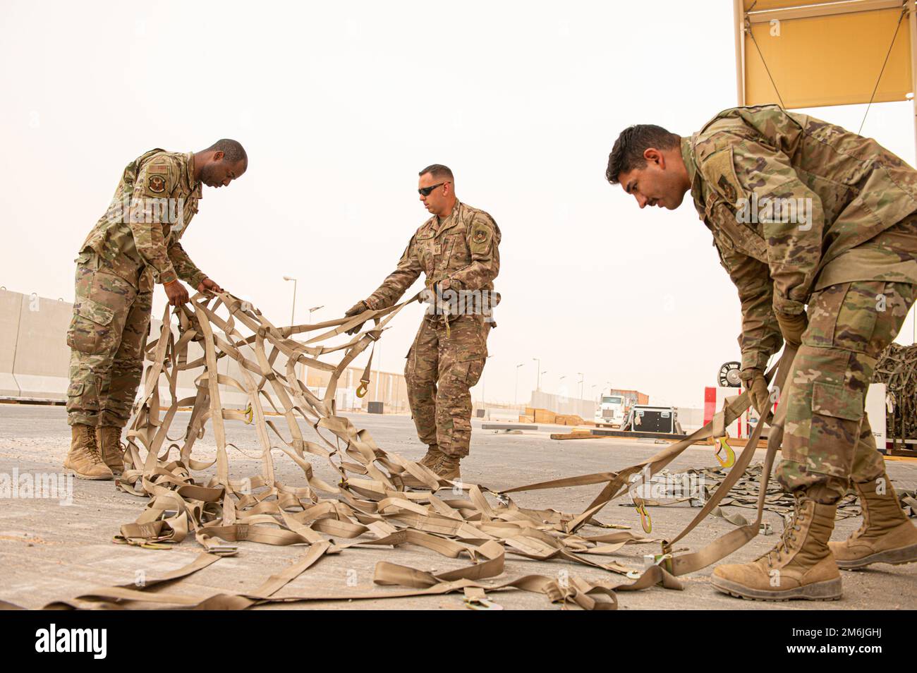 STATI UNITI I militari con il Centro operativo del Terminal aereo, 378th Squadron della logistica di spedizione, raddrizzano le cinghie di carico, alla base aerea del principe Sultan, Regno dell'Arabia Saudita, 28 aprile 2022. Gli specialisti del trasporto aereo hanno la responsabilità di gestire in modo sicuro le merci e i passeggeri e di garantire che tutto e tutto il personale di un aereo militare venga trasportato in modo sicuro e rapido. Foto Stock