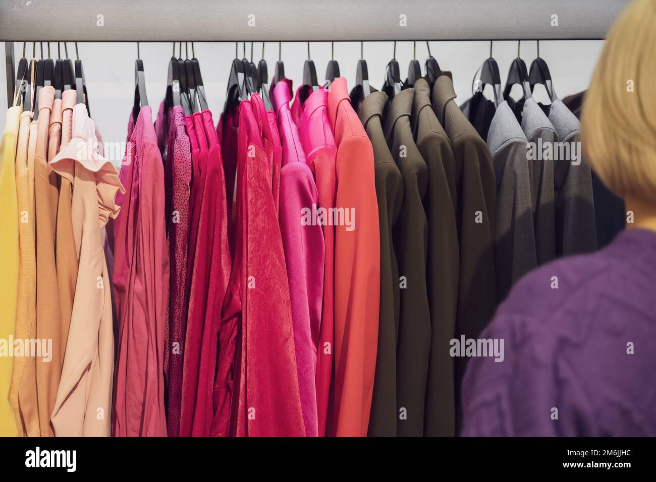 I vestiti delle donne appendono in una fila su un appendiabiti. Scegli un outfit in un negozio di moda Foto Stock