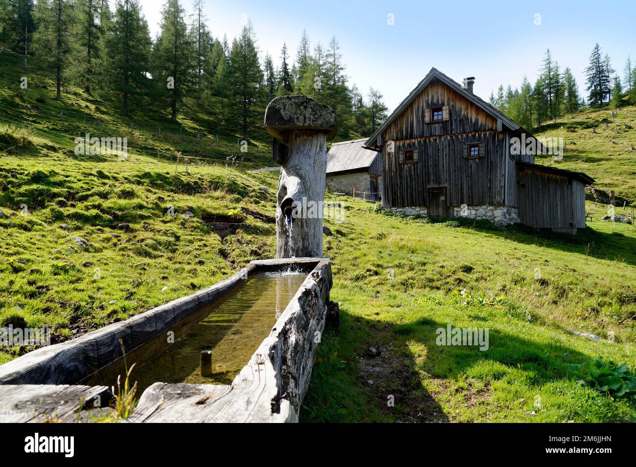Cabina alpina e un canale d'acqua ai piedi del monte Dachstein, nel villaggio alpino Neustatt Alm, nelle Alpi austriache di Steiermark Foto Stock