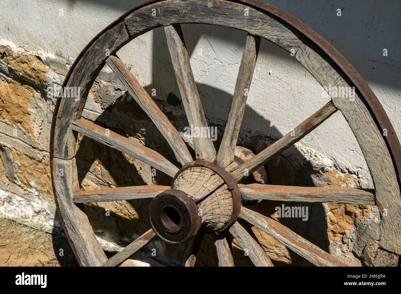 Vecchia ruota di legno del carro di paese come decorazione della parete della casa rurale Foto Stock