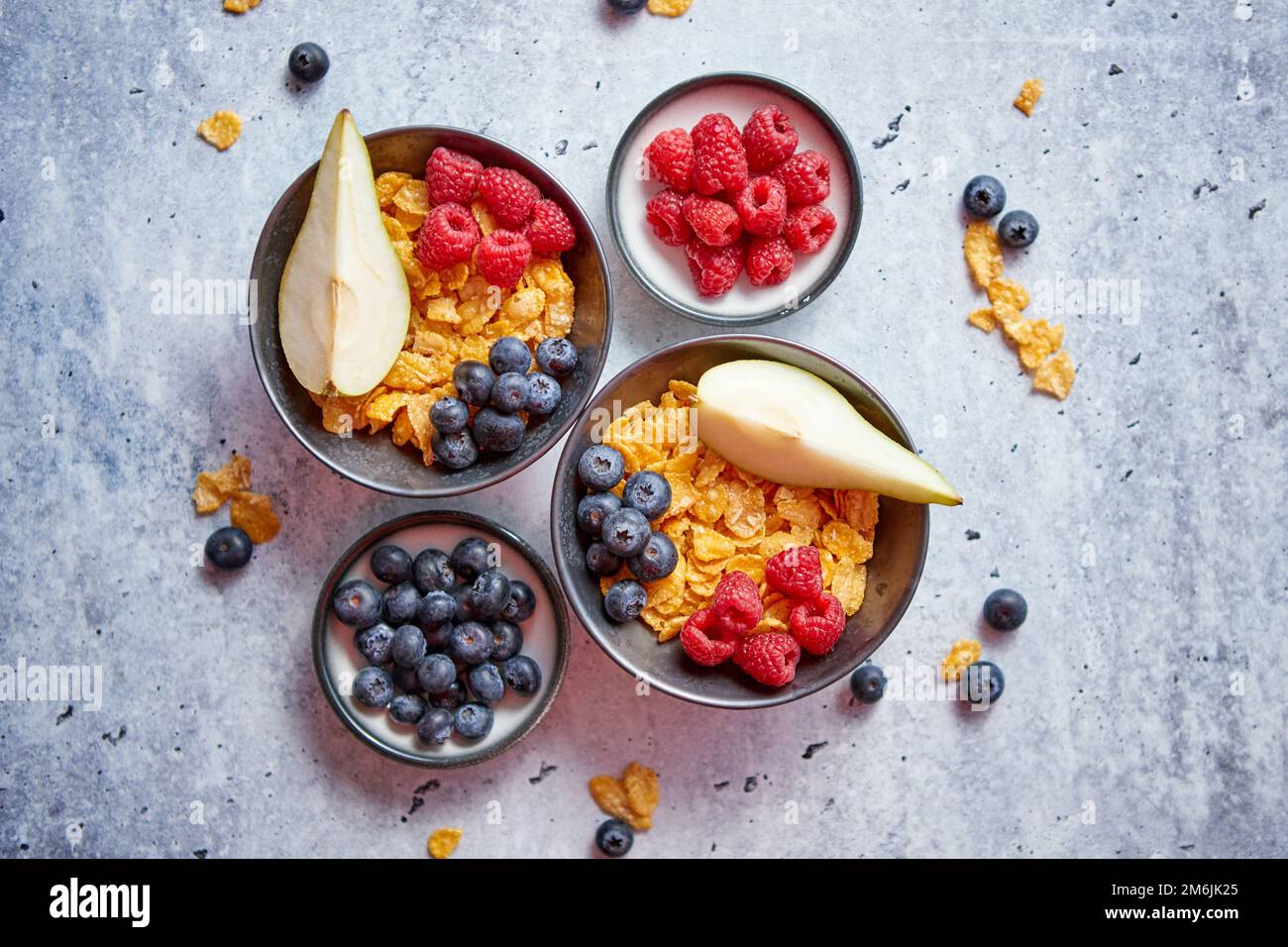 Golden corn flakes con frutti freschi di lamponi mirtilli e pera in vaso in ceramica Foto Stock