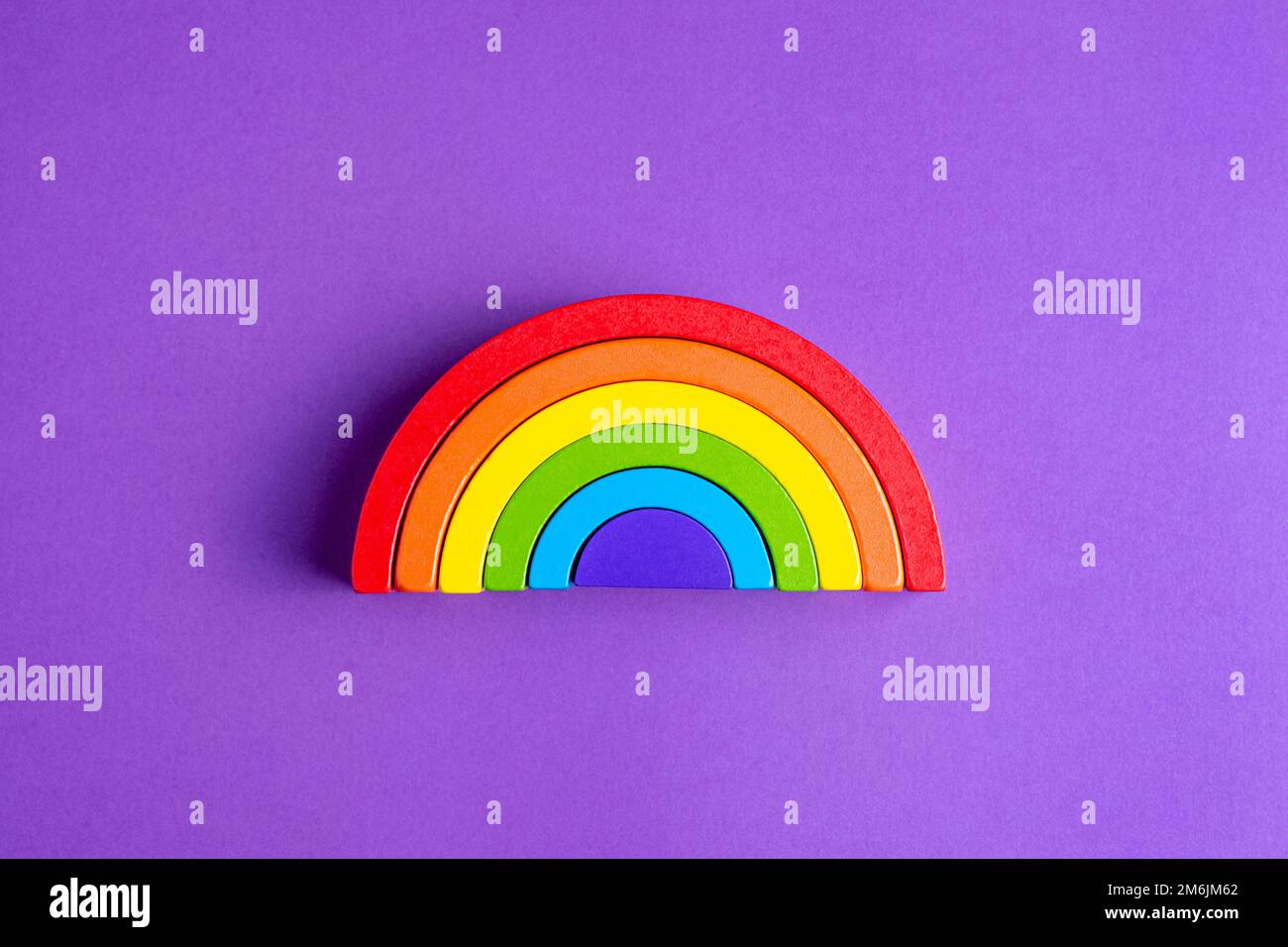 Variopinto arcobaleno di figure umane in legno di Waldorf in un montessori pedagogia pedagogia su sfondo viola, concetto di gioco per bambini Foto Stock