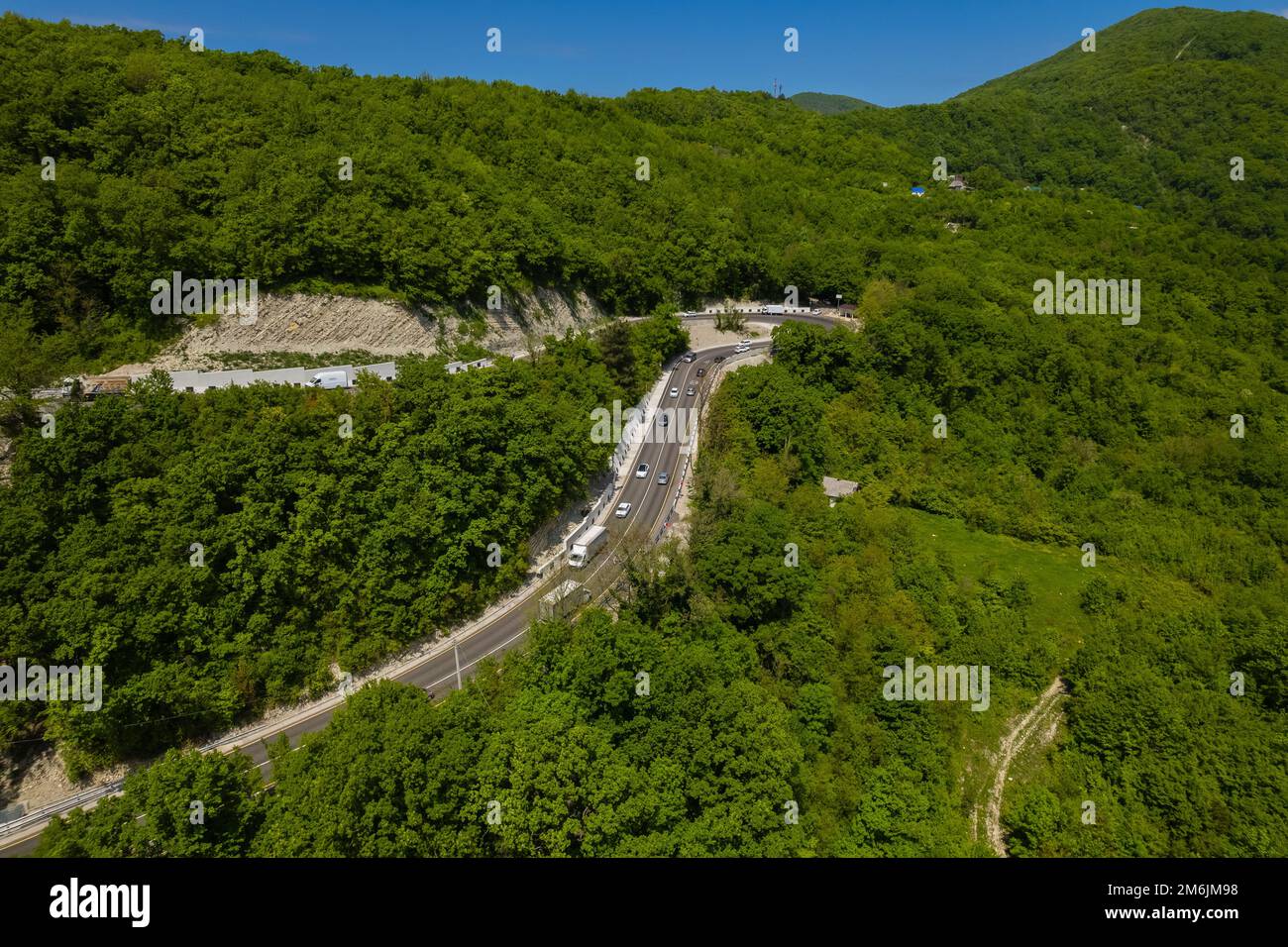 Vista aerea della strada tortuosa dal passo di montagna alto. Ottima gita su strada attraverso i fitti boschi. Vista panoramica degli uccelli. Foto Stock