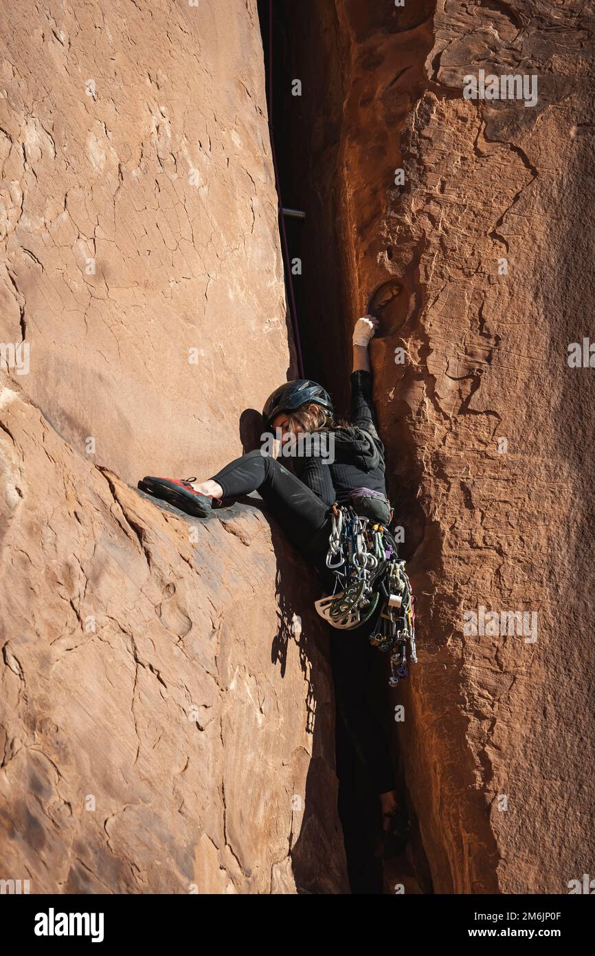 Vista dall'angolo basso di una determinata donna che si arrampica sulla roccia del deserto Foto Stock