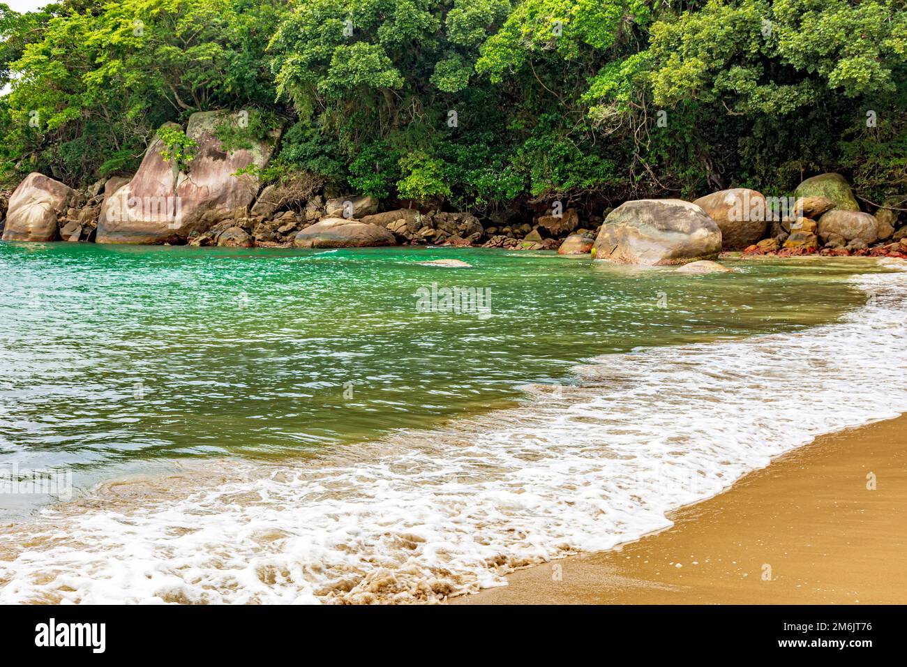 Spiaggia incontaminata e deserta, circondata da rocce e foresta pluviale Foto Stock