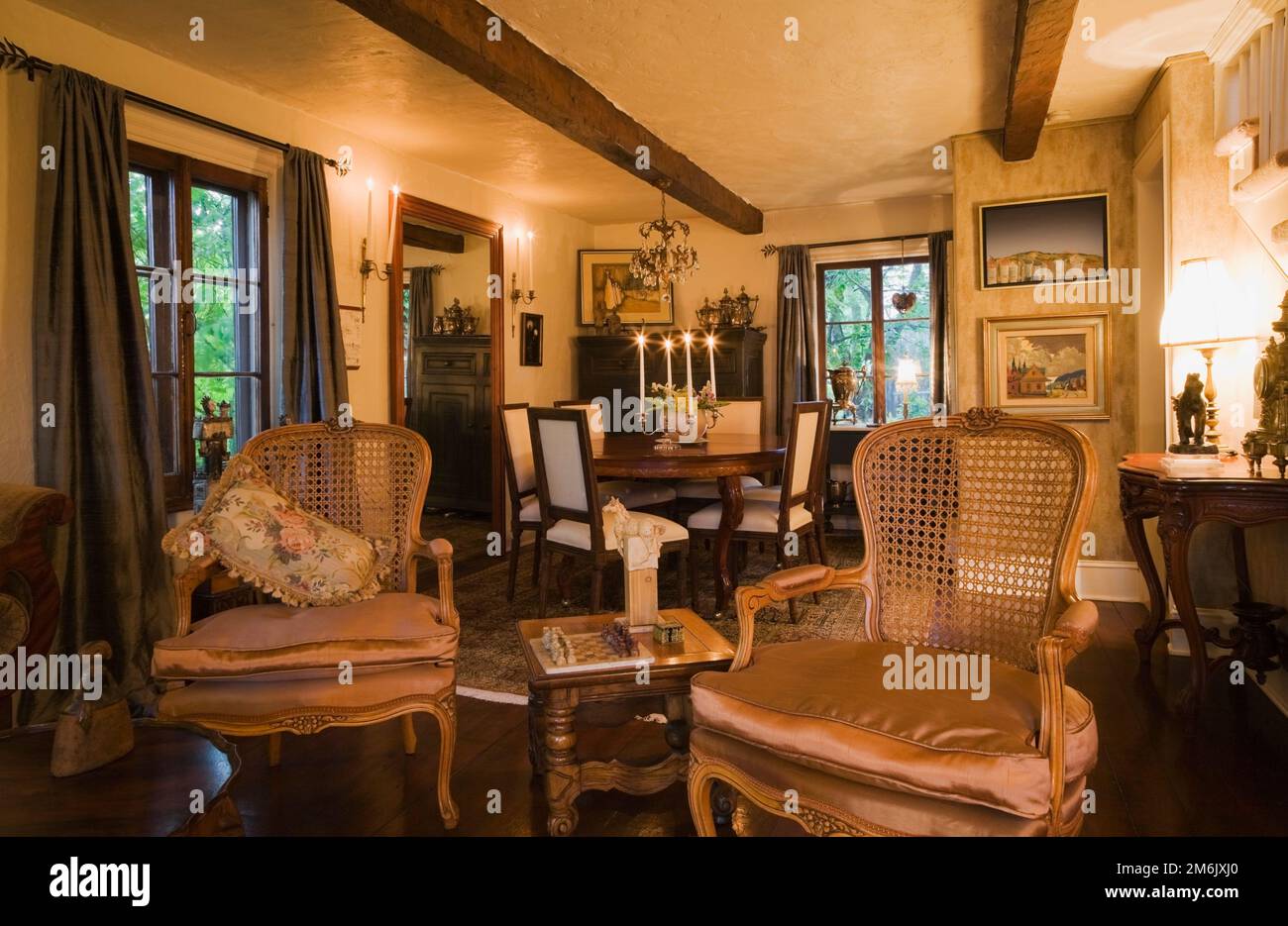 Antiche poltrone con schienale alto e griglia in legno nel soggiorno che guardano alla sala da pranzo all'interno di una vecchia casa in stile cottage del 1809. Foto Stock