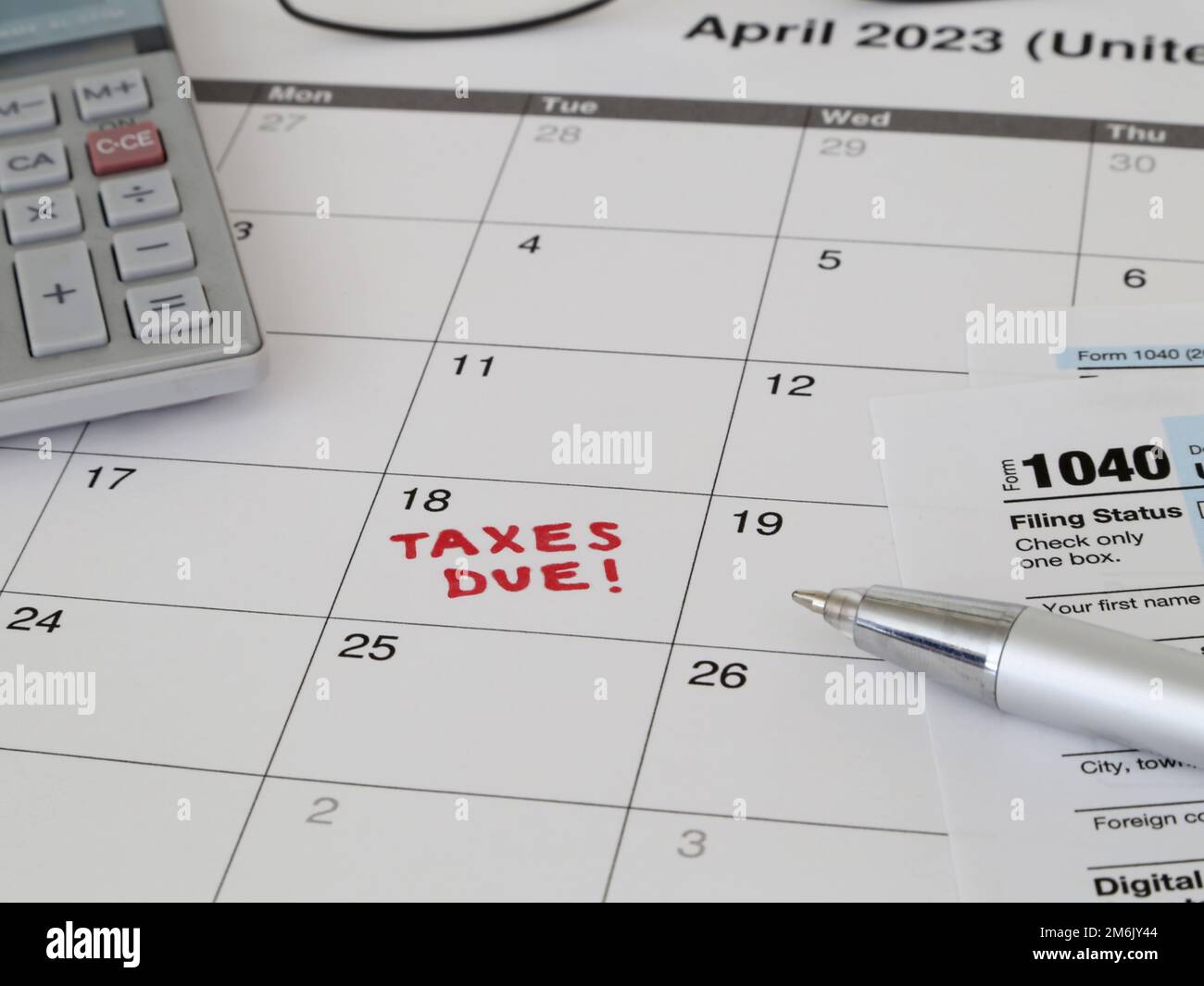 Un calendario 2023 che osserva il 18 aprile USA Internal Revenue Service IRS termine di deposito del reddito per l'anno 2022 tasse è mostrato in primo piano. Foto Stock