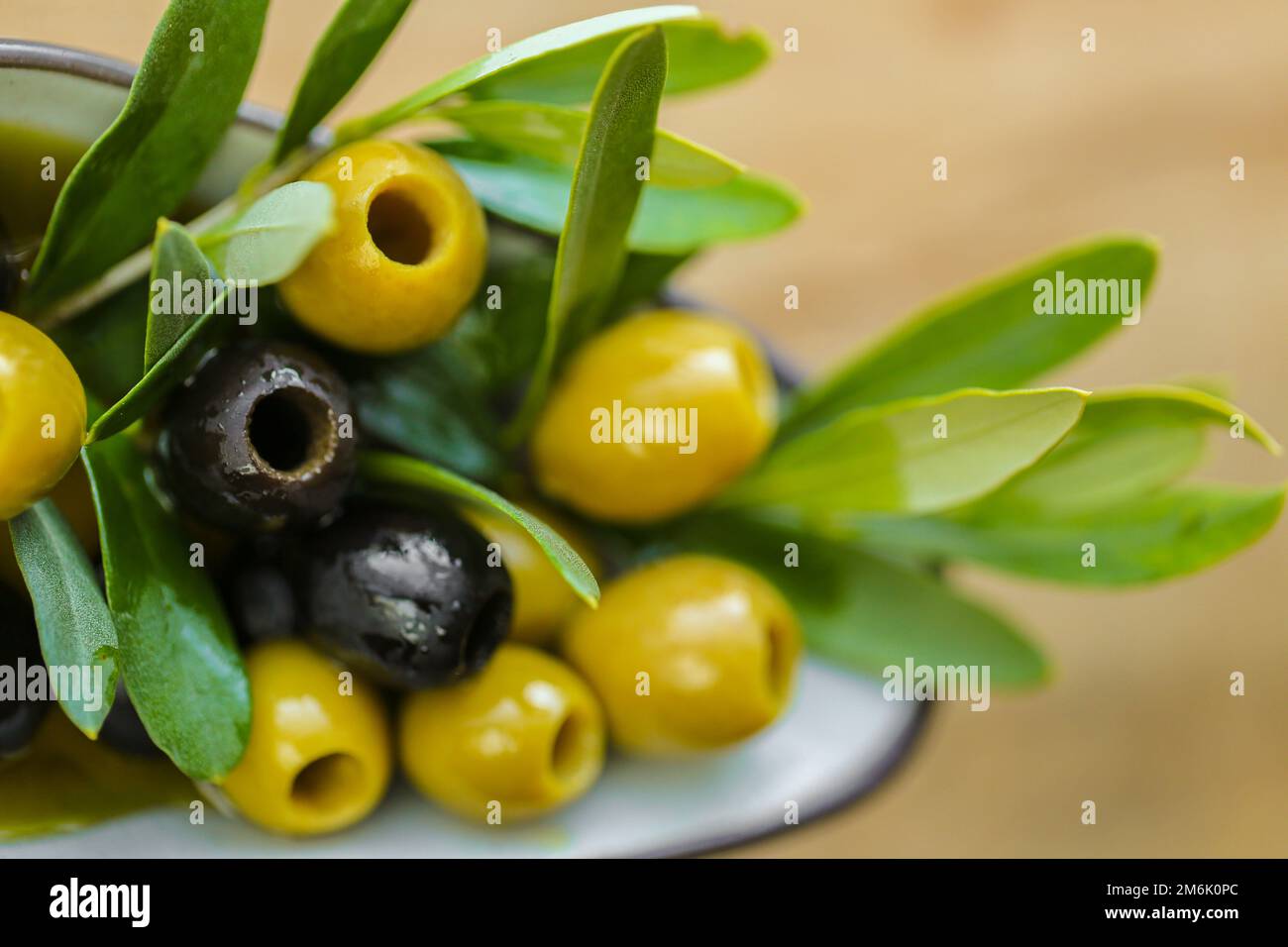 Olive e olio d'oliva. Ingrediente della cucina mediterranea. Olive nere e verdi e un ramo di olive verdi primo piano in olio d'oliva . Olive biologiche fresche Foto Stock