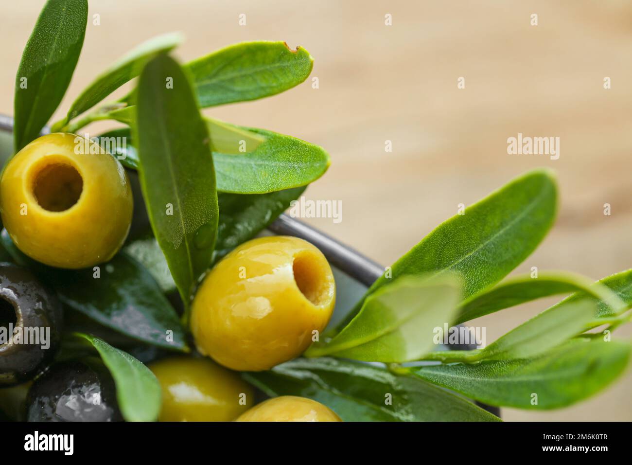 ingrediente della cucina mediterranea. Olive nere e verdi e un ramo di olive verdi primo piano in olio d'oliva su un tavolo di legno. Olive fresche biologiche e. Foto Stock