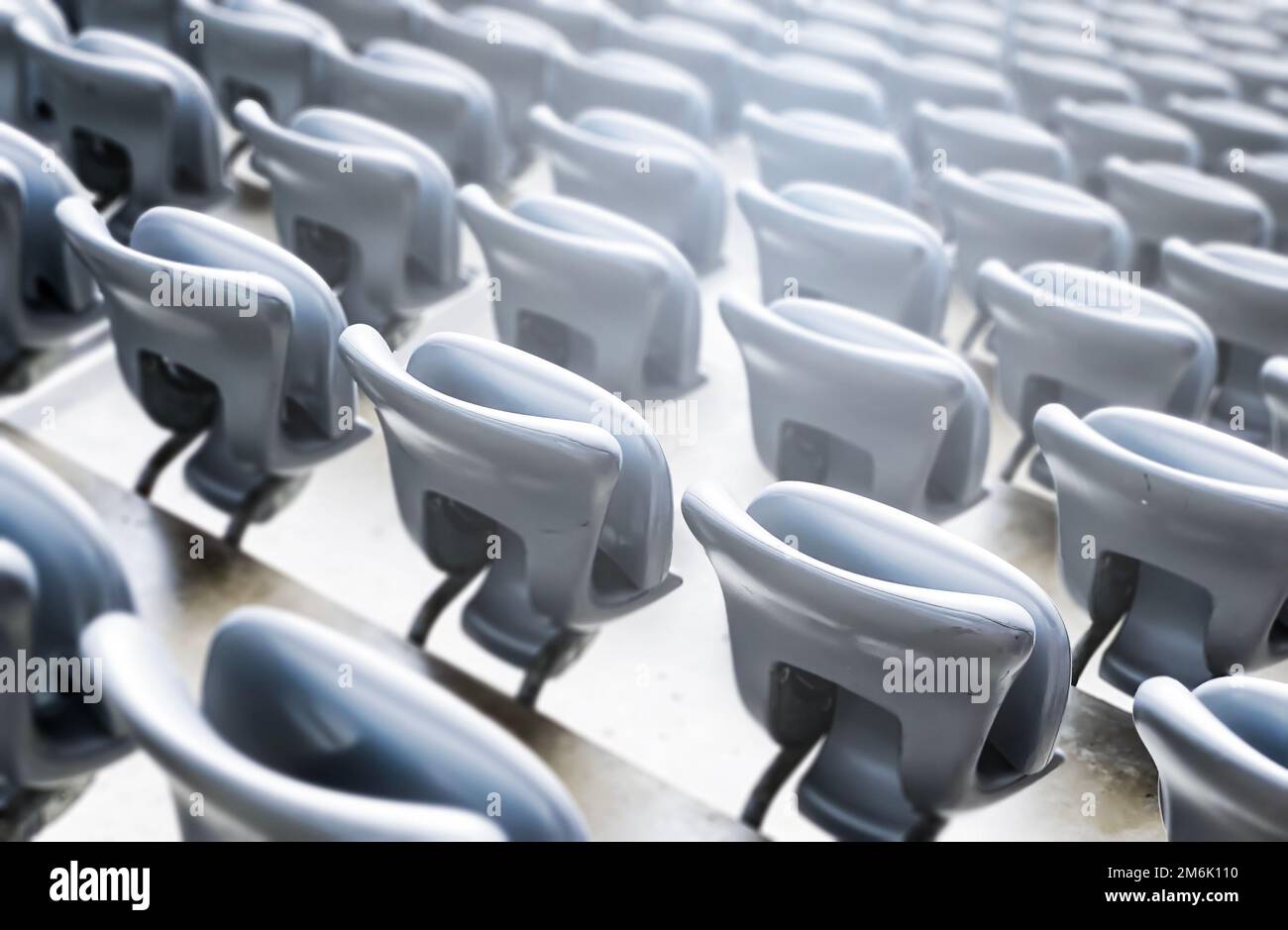 Sedie grigie vuote all'interno di uno stadio. Sedili in plastica disposti in file. Ripetizione e simmetria. Foto Stock