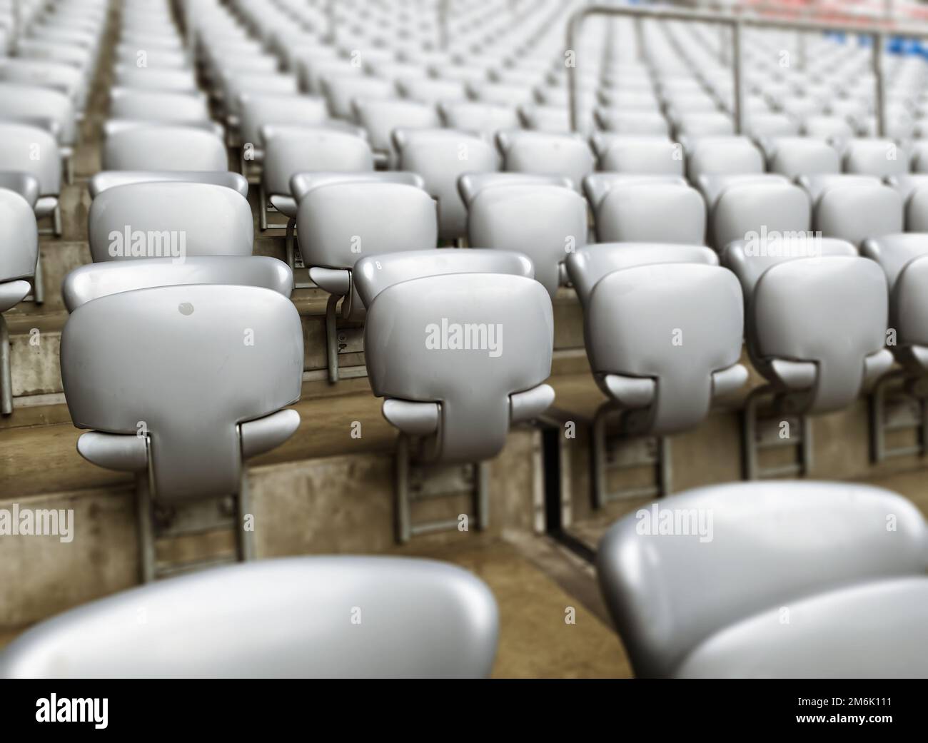 Sedie grigie vuote all'interno di uno stadio. Sedili in plastica disposti in file. Ripetizione e simmetria. Foto Stock
