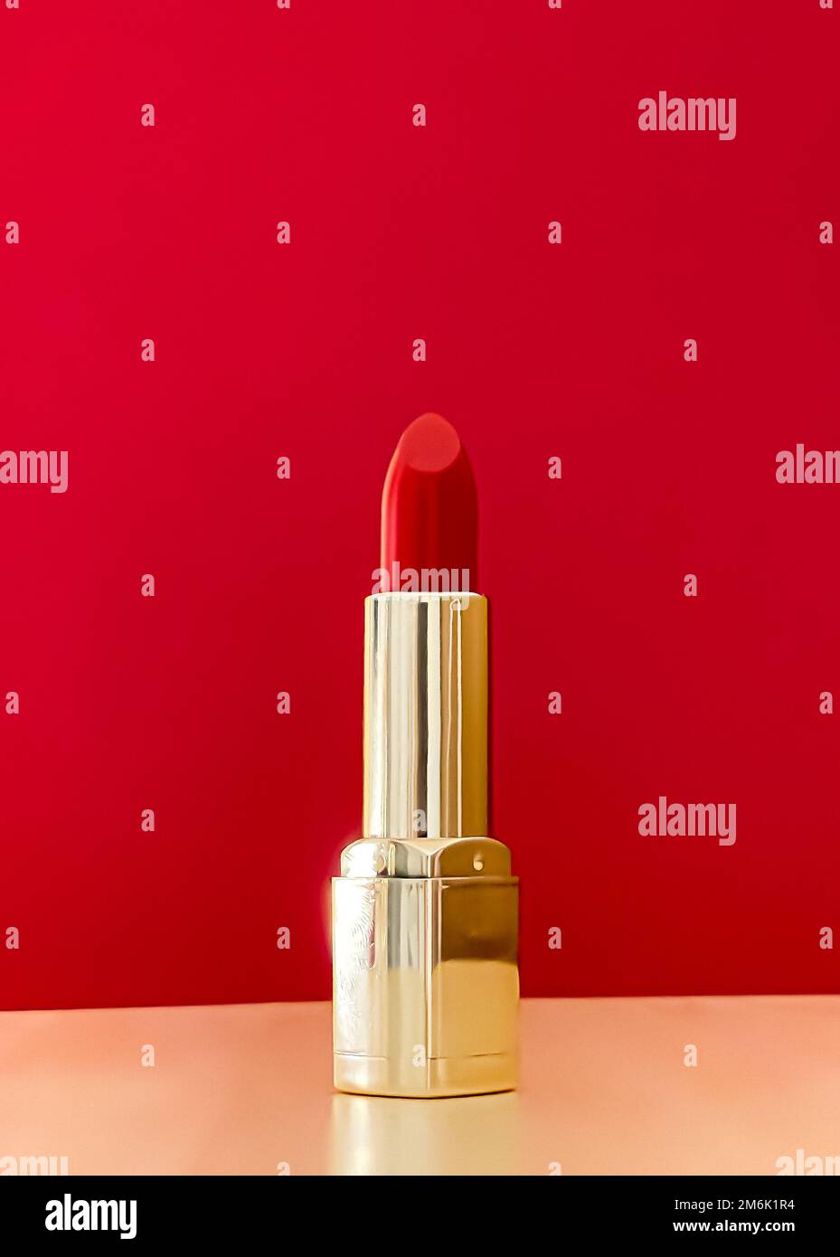 Rossetto rosso in tubo dorato su sfondo colorato, trucco di lusso e cosmetici per il design di prodotti di marca di bellezza Foto Stock