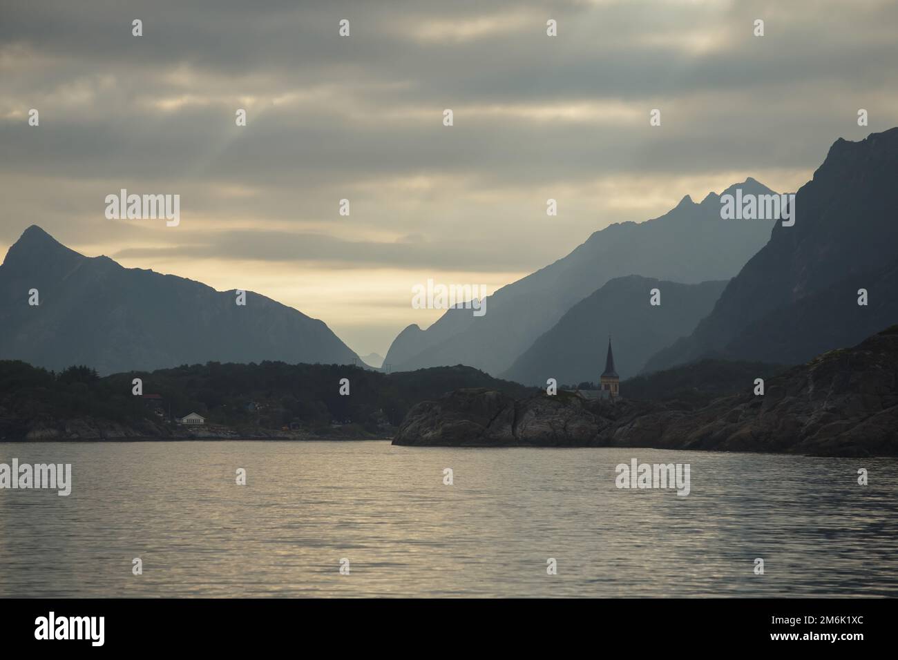 Mare norvegese, costa rocciosa con cieli spettacolari, il sole si spezza tra le nuvole, scogliere a strapiombo, piccole isole illuminate Foto Stock