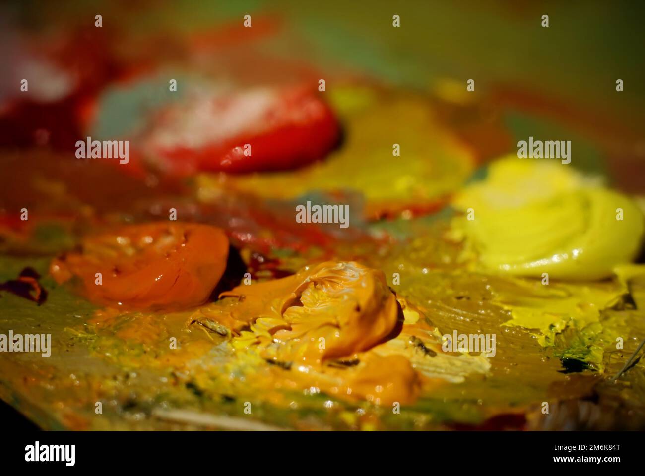 La pittura dell'olio di miscela di spazzola dell'artista sulla tavolozza sta tenendo nel suo closeup della mano Foto Stock