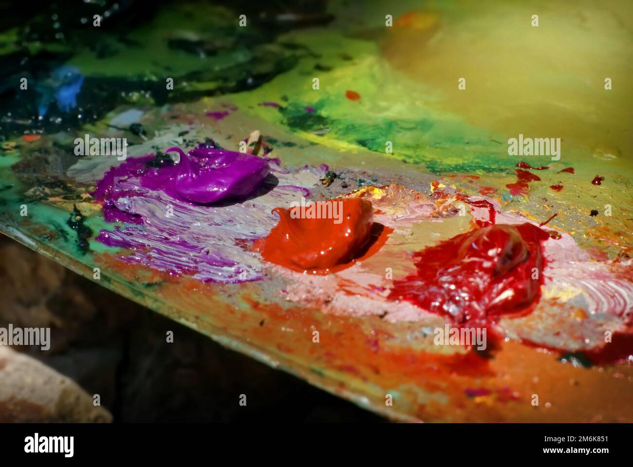 La pittura dell'olio di miscela di spazzola dell'artista sulla tavolozza sta tenendo nel suo closeup della mano Foto Stock