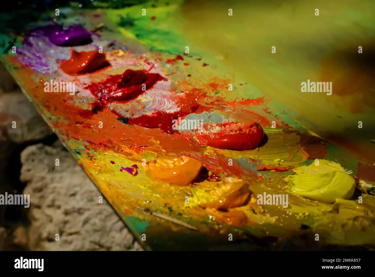 La pittura dell'olio di miscela di spazzola dell'artista sulla tavolozza sta tenendo nel suo closeup della mano Foto Stock