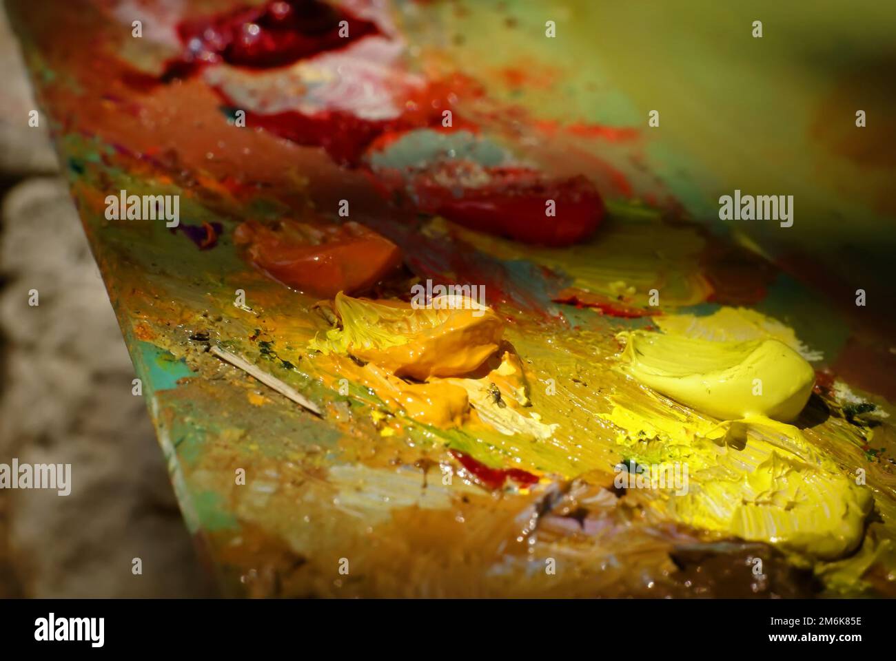 La pittura dell'olio di miscela di spazzola dell'artista sulla tavolozza sta tenendo nel suo closeup della mano Foto Stock
