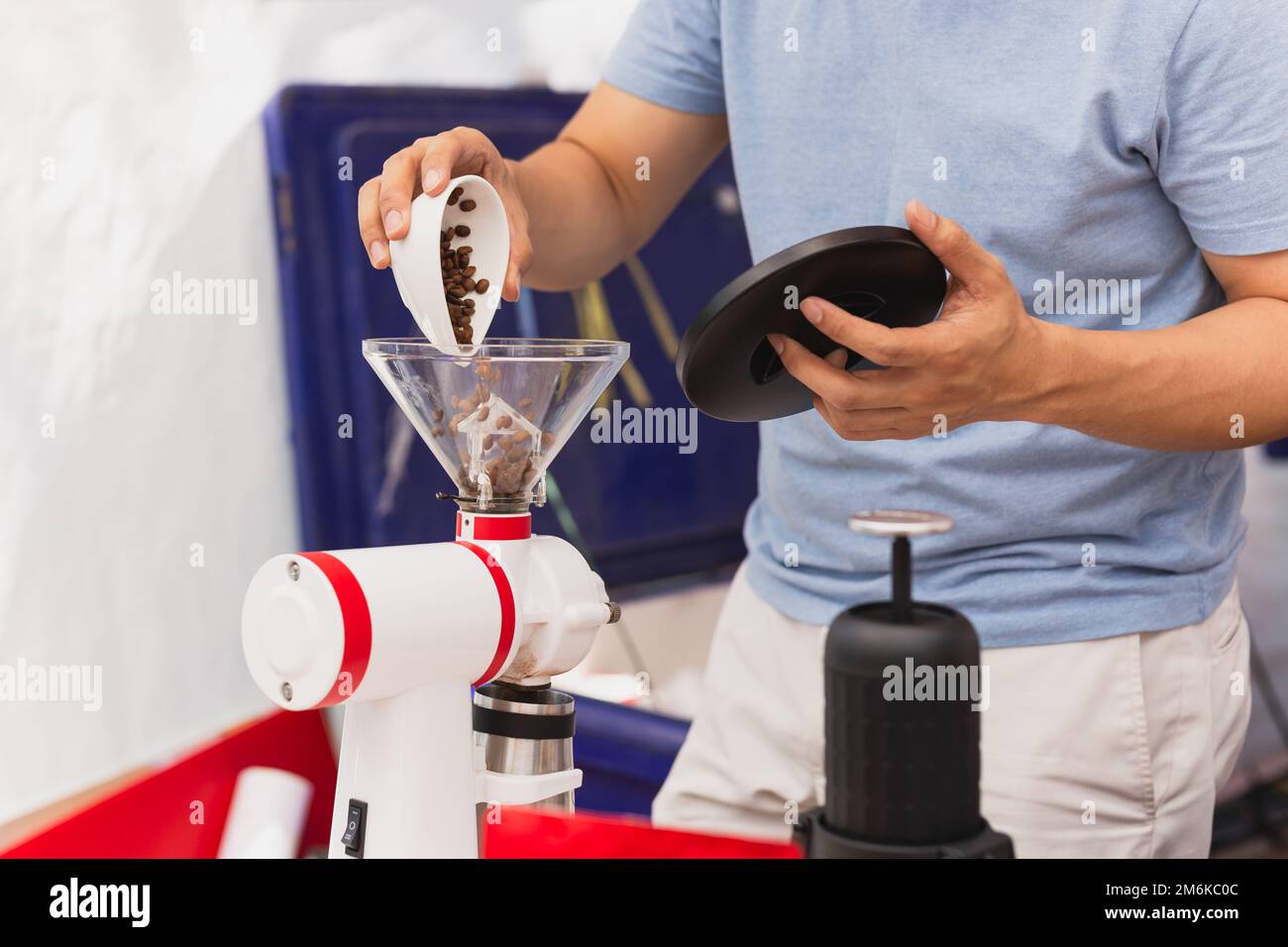 Barista che versa i chicchi di caffè nel macinacaffè per preparare il caffè nero. Foto Stock