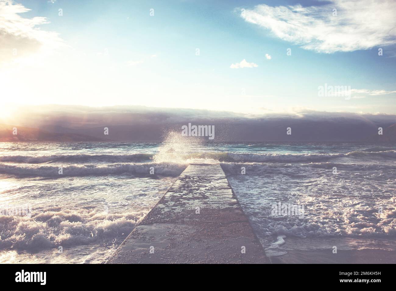 Grandi onde che si infrangono sul molo di pietra, con il tempo tempestoso. Foto Stock