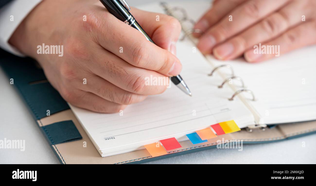 Mani di un uomo d'affari che scrive un programma o che registra le idee in un diario Foto Stock