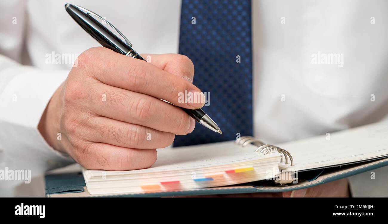 Mani di un uomo d'affari che scrive un programma o che registra le idee in un diario Foto Stock