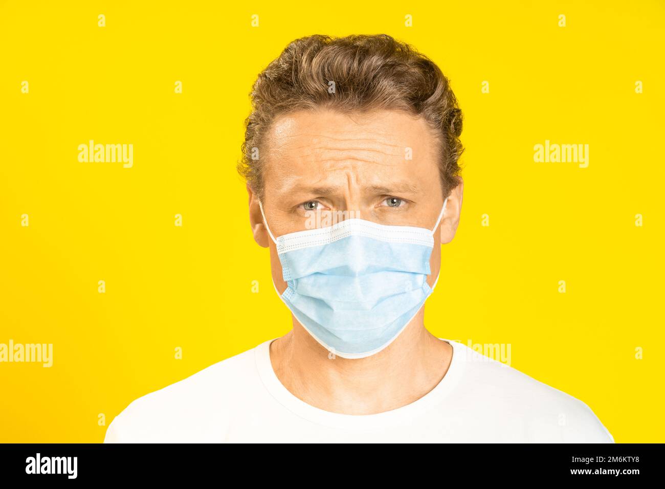 Triste bell'uomo che indossa la maschera medica prevenzione coronavirus pandemico o monkeypox. Bell'uomo in t-shirt bianca e medica Foto Stock