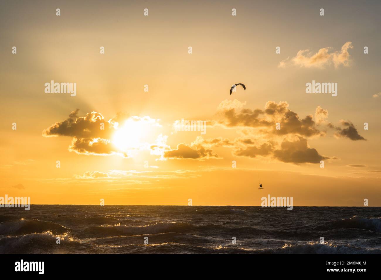 Kitesurfer fare trucchi al tramonto sul mar baltico Foto Stock