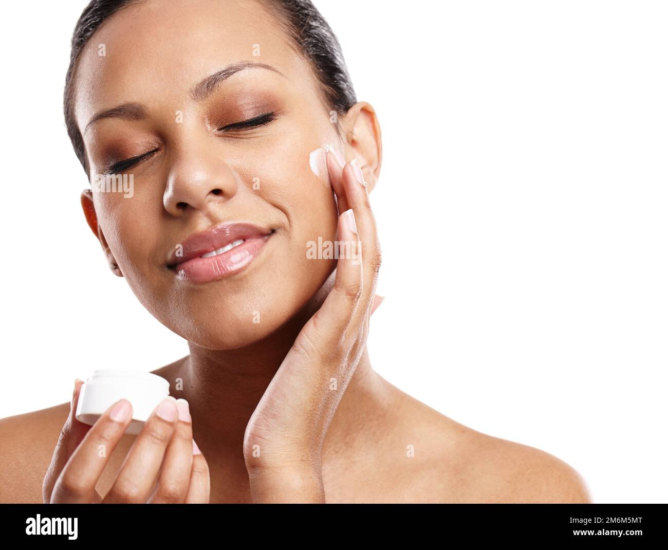 Senti la morbidezza. una bella giovane donna che applica la crema per il viso mentre si trova in uno studio. Foto Stock