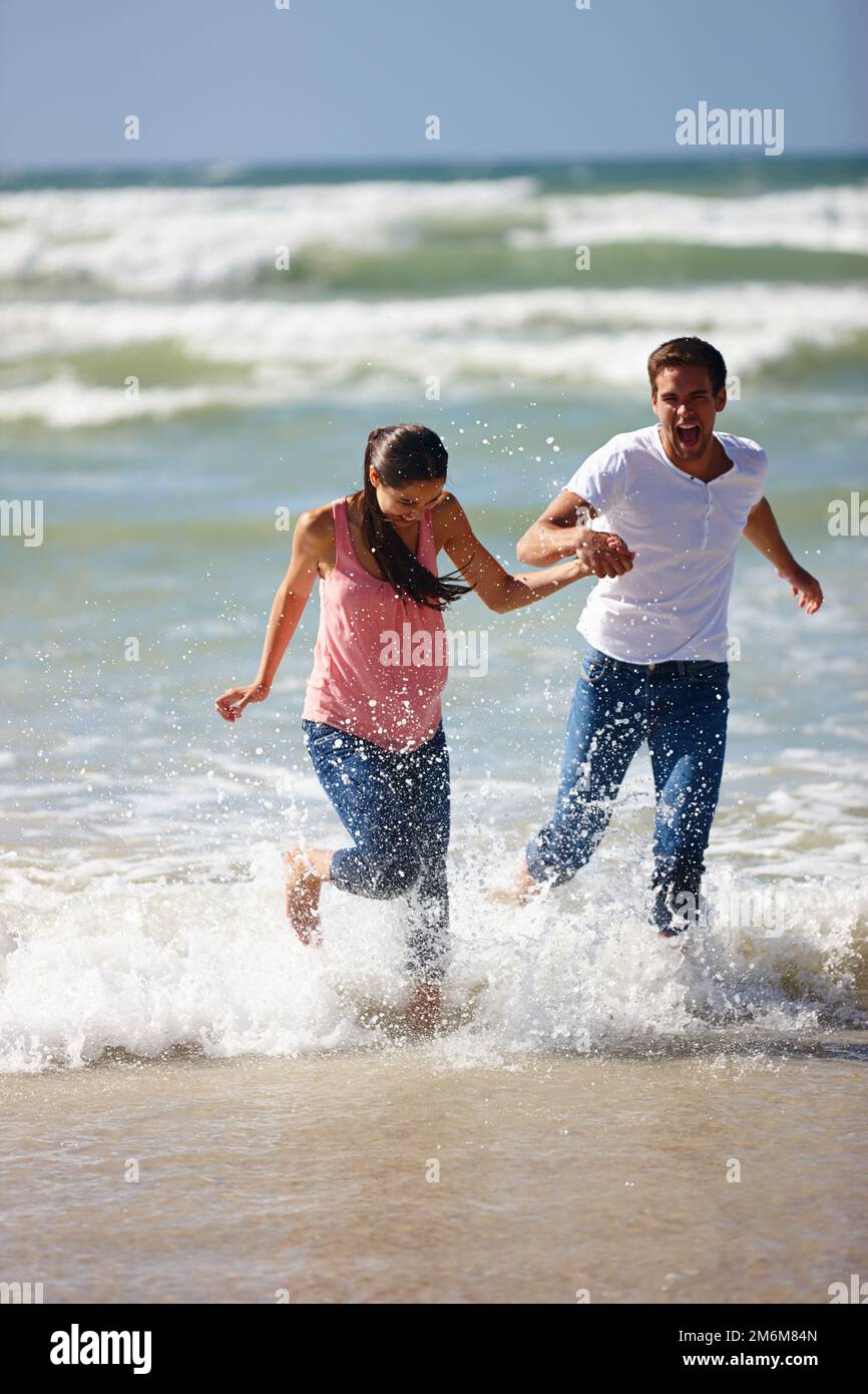 Lascia scappare e inizia una vita nostra. una giovane coppia è giocosa sulla spiaggia. Foto Stock