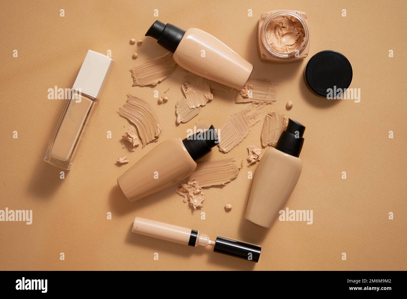 Bottiglie di fondazione makeup e campioni su sfondo beige Foto Stock