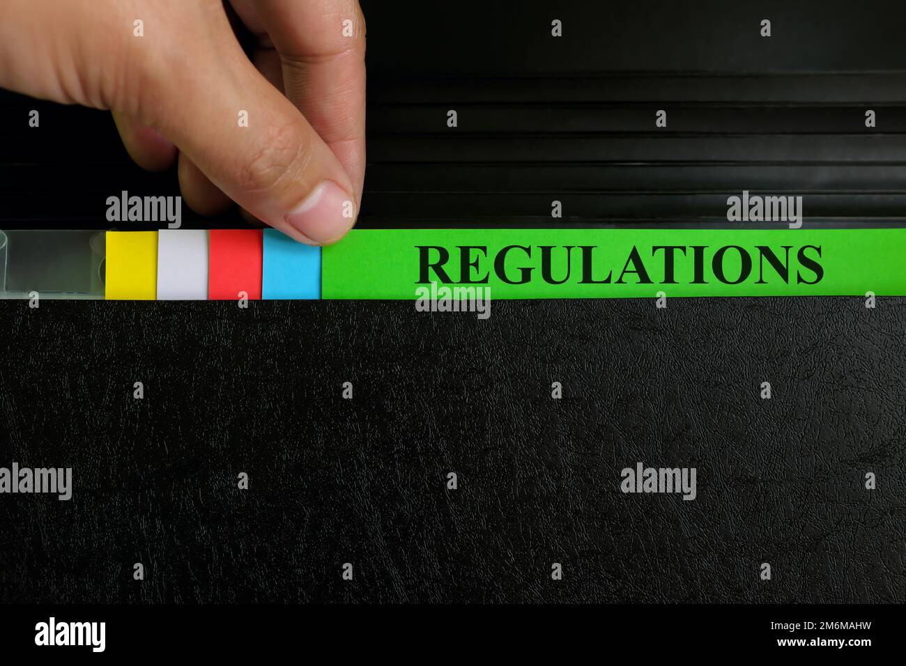 Registrazione del file delle norme per il prelievo a mano nella cartella raccoglitore nero. Concetto di regolamentazione aziendale e governativa. Foto Stock