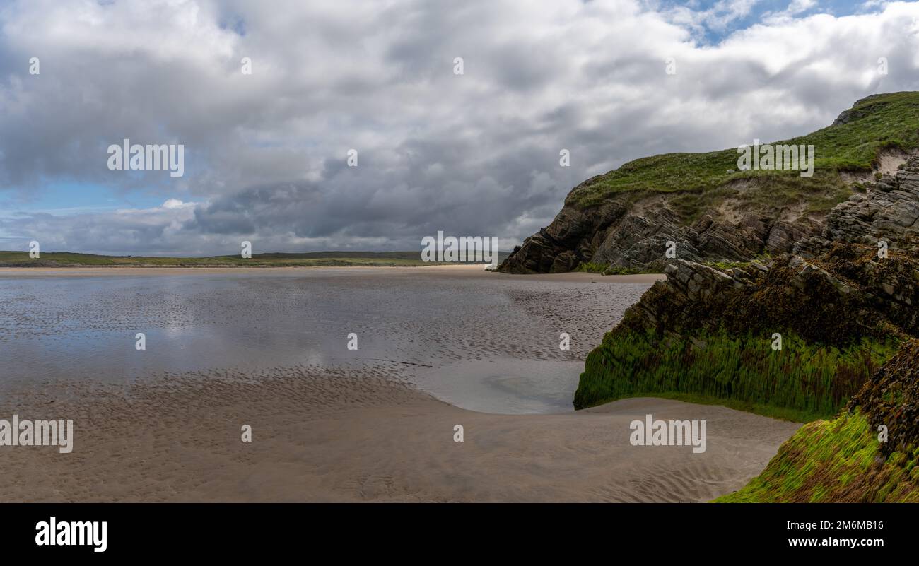 Spiaggia di Maghera sabbia dorata con rocce ricoperte di alghe e scogliere in primo piano Foto Stock