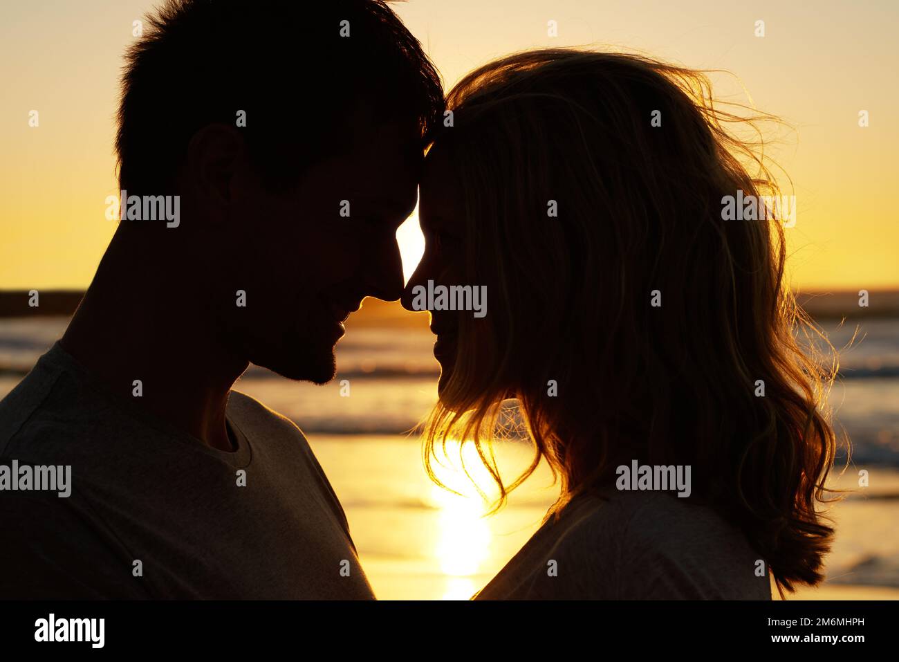 Eskimo si bacia sulla spiaggia. Romantico scatto di una coppia nasi toccare sulla spiaggia al tramonto. Foto Stock