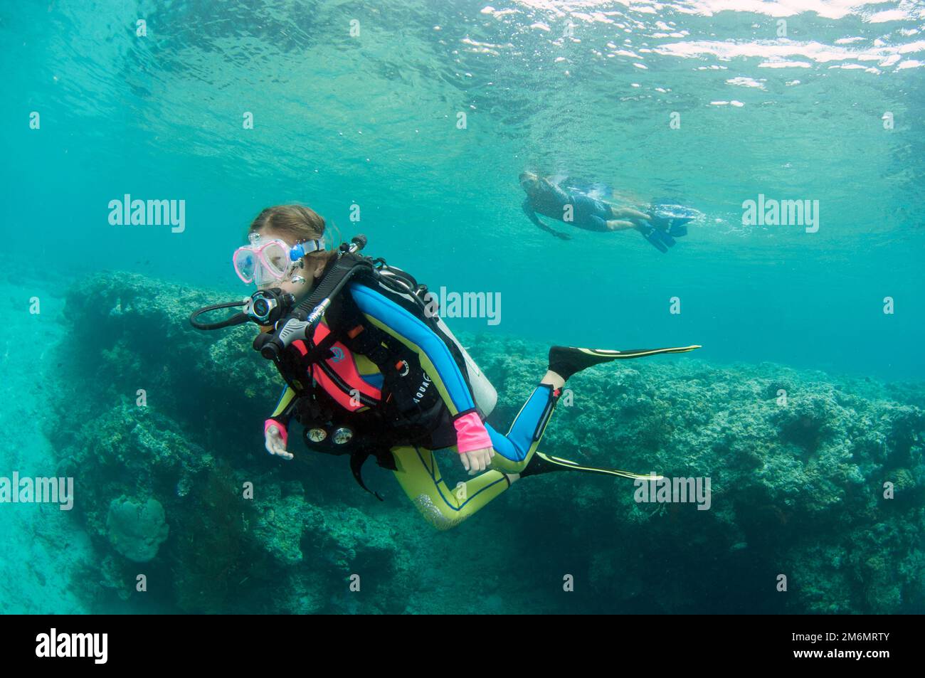 Ragazza di 9 anni che diving con madre snorkeling in background, Post 2 sito di immersione, Menjangan Island, Buleleng, Bali, Indonesia Foto Stock