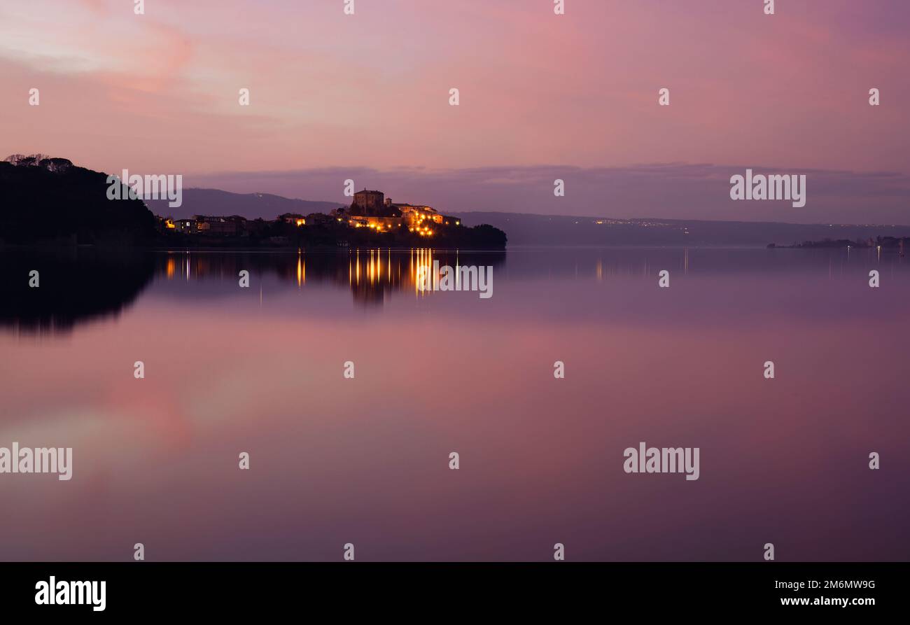 Lago di Bolsena e Capodimonte, una cittadina, in un roseo tramonto invernale. Panorama visto da Marta Foto Stock