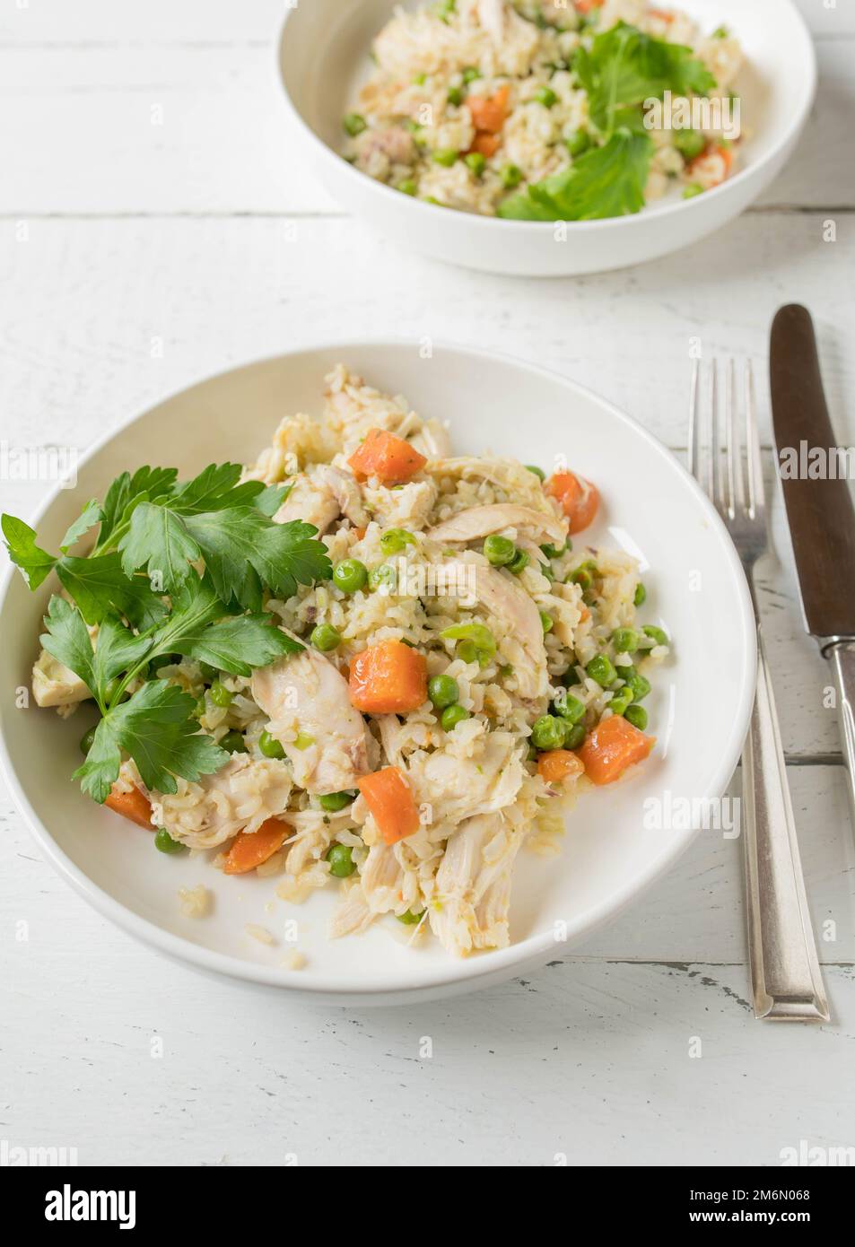 Far rosolare il riso con pollo e verdure su un piatto su fondo bianco. Pasto a basso contenuto di grassi per un'alimentazione sana, fitness, dieta o costruzione muscolare Foto Stock