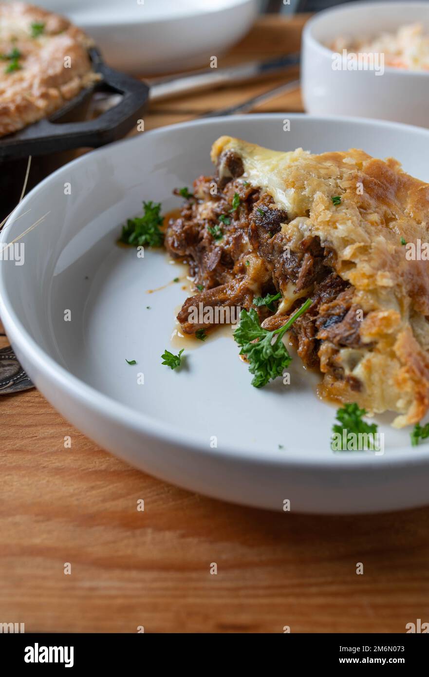 Fetta di bistecca e torta al formaggio su un piatto. Cotto in una padella di ghisa con gambi di manzo Foto Stock