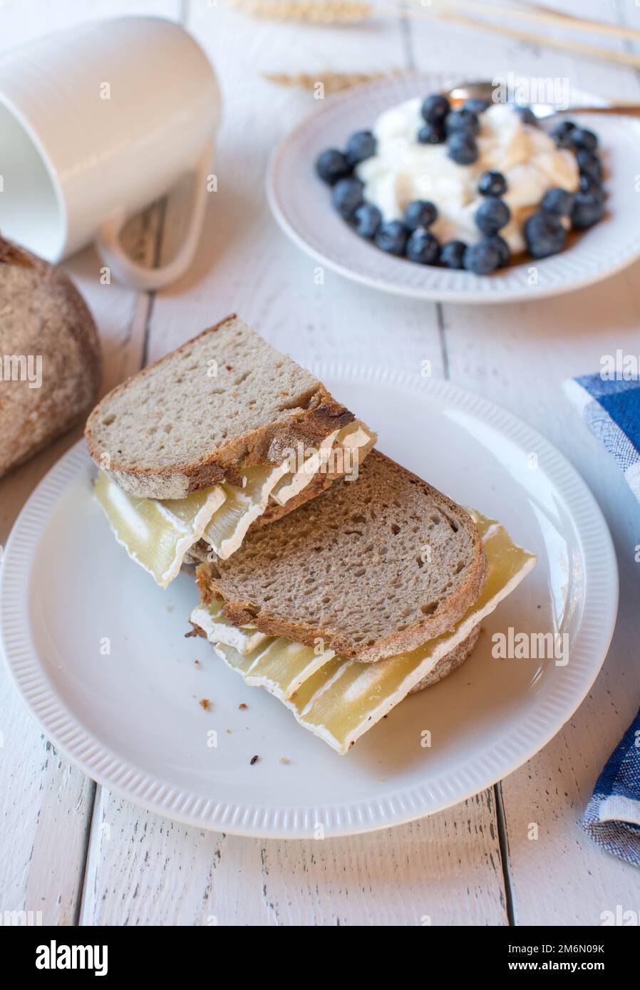 Un sano panino da colazione con pane di pasta madre e formaggio di quark. Servito con yogurt fresco e frutti di bosco su sfondo bianco Foto Stock