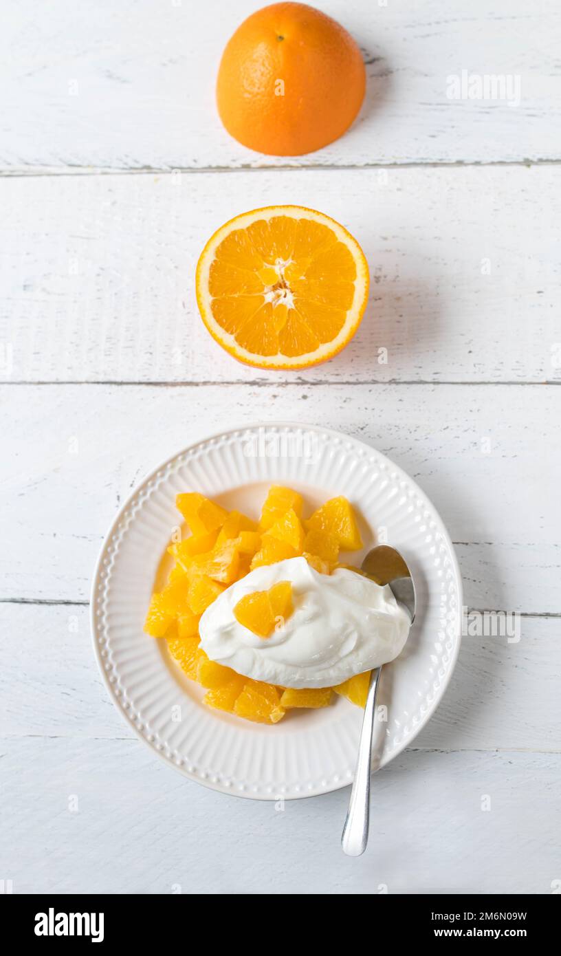 Dessert all'arancia con arance tritate e yogurt naturale per un'alimentazione sana. Servito su un piatto su sfondo bianco con spazio per il testo Foto Stock