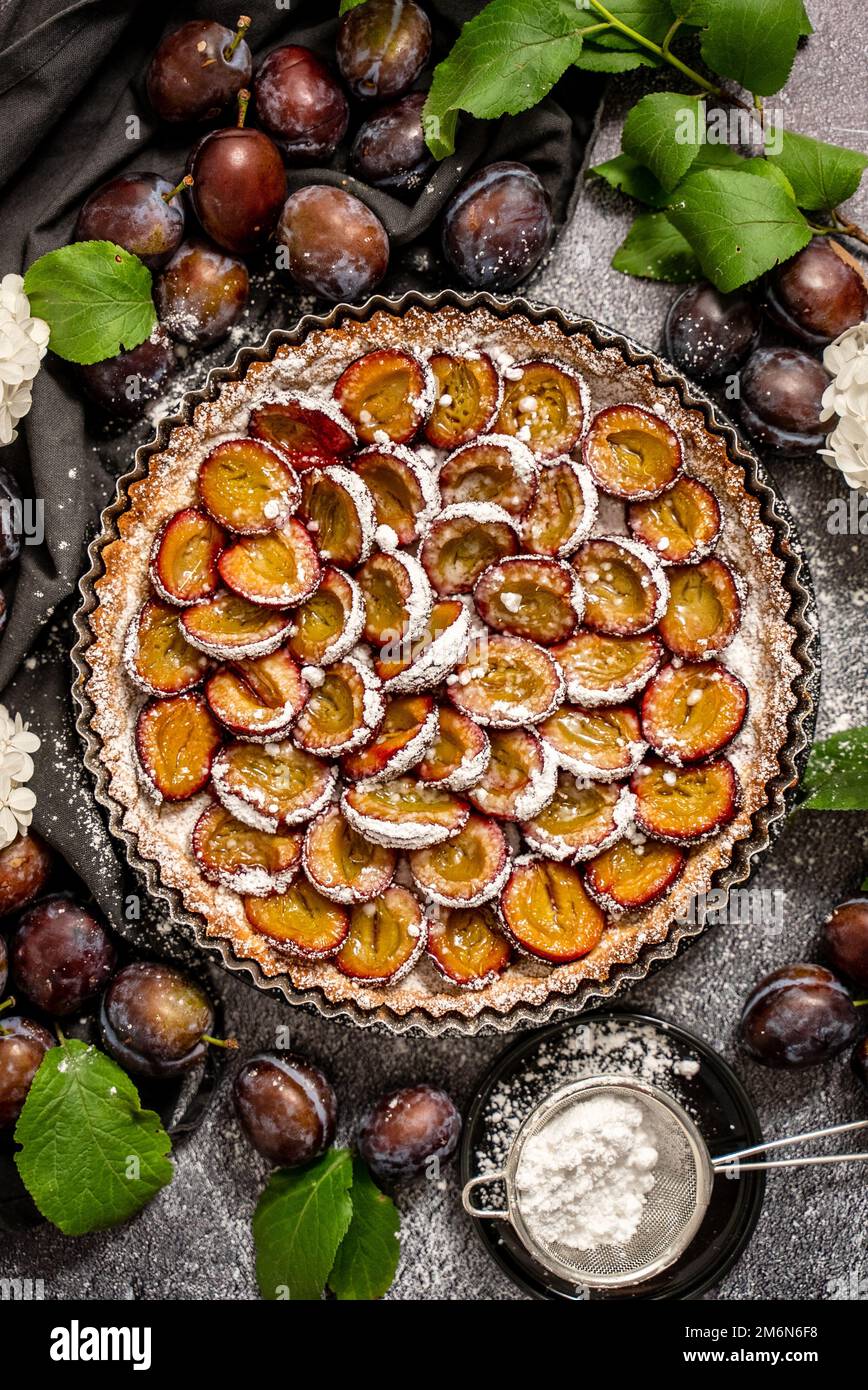 Torta di prugne fatta in casa deliziosa con zucchero in polvere posto sul tavolo Foto Stock