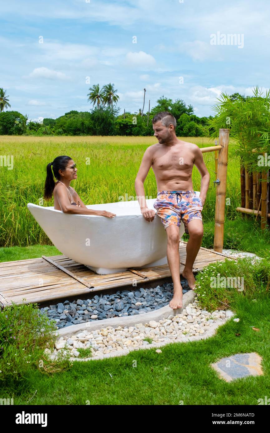 Uomini e donne in vasca da bagno fuori in vacanza in una famiglia in Thailandia con risaia verde campo Foto Stock
