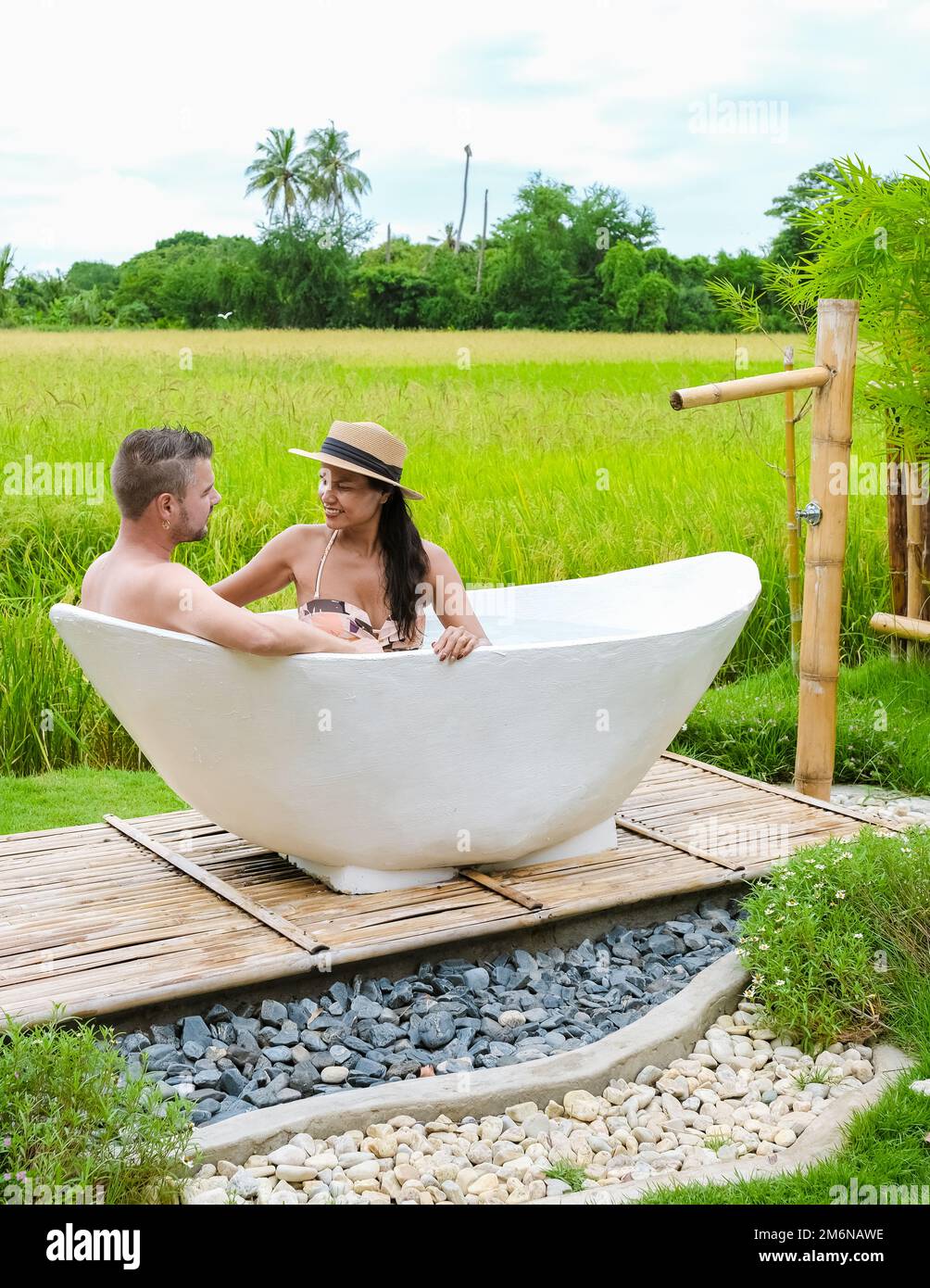 Uomini e donne in vasca da bagno fuori in vacanza in una famiglia in Thailandia con risaia verde campo Foto Stock