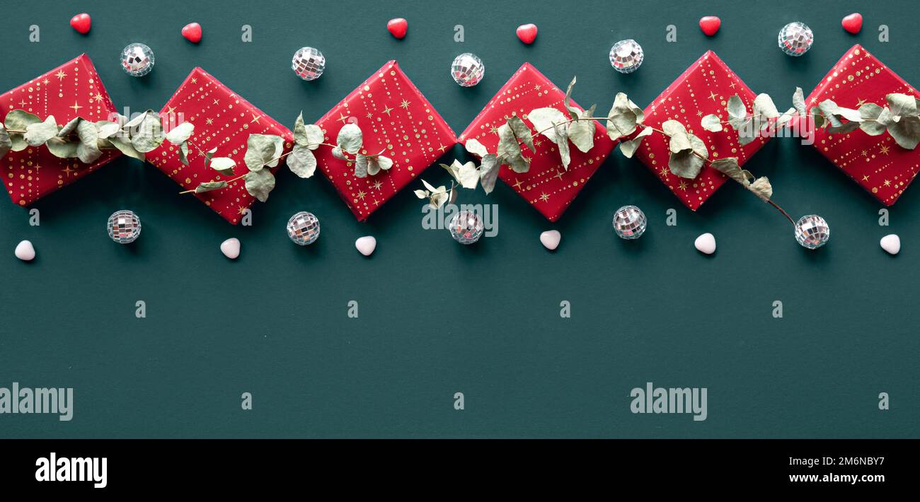 Contorno decorativo rosso invernale con scatole regalo, palle da discoteca  ed eucalipto. Piatto su tessuto di lino blu. Panorama con regali avvolti e  asciutti Foto stock - Alamy