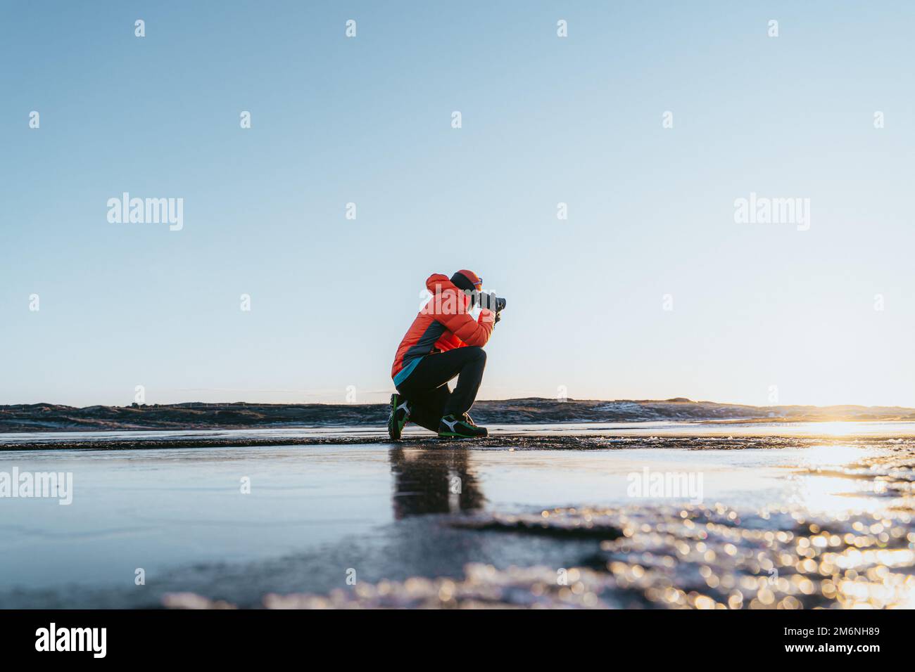 l'uomo che fotografa il tramonto si accovacciò Foto Stock