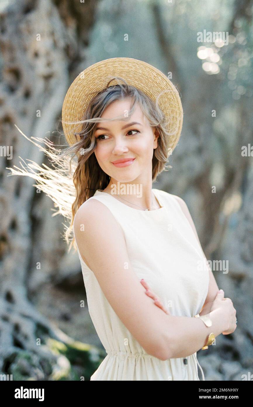 Donna sorridente in un cappello di paglia incrociò le braccia sul petto Foto Stock